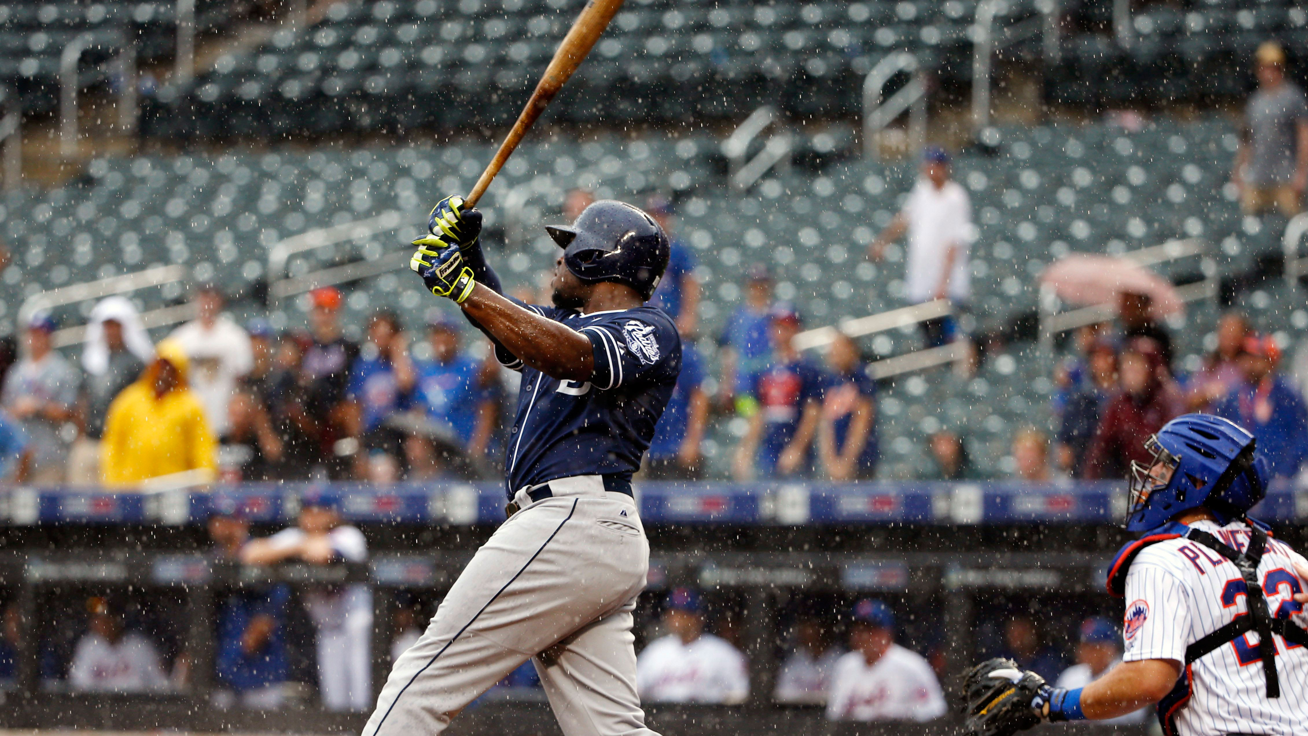 As rain falls, San Diego Padres' Justin Upton, left, hits a ninth-inning three-run home run off New York Mets relief pitcher Jeurys Familia. (Kathy Willens/AP)
