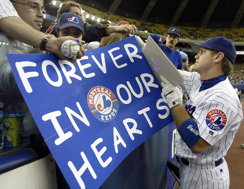 Montreal Expos former pitcher and now coach Claude Raymond, left, consoles  Brad Wilkerson as they say farewell to fans following the team's final home  game against the Florida Marlins in Montreal, Sept.