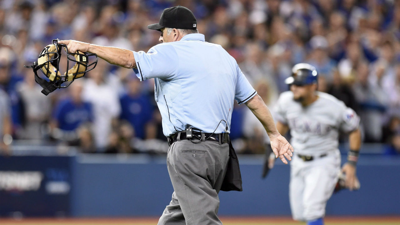 Home plate umpire Dale Scott, left, signals for Texas Rangers' Rougned Odor to score after conferring with the base umpires to confirm an error by Toronto Blue Jays catcher Russell Martin (not shown) on the play during the seventh inning of game 5 American League Division Series baseball action in Toronto on Wednesday, Oct. 14, 2015.