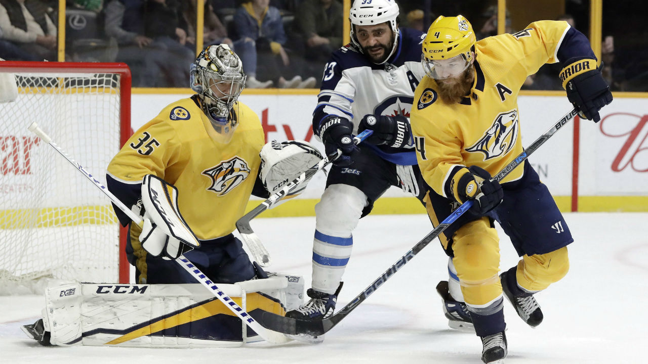 Winnipeg Jets' Dustin Byfuglien and Nashville Predators' Ryan Ellis chase a rebound after Predators goalie Pekka Rinne blocked a shot in an NHL hockey game